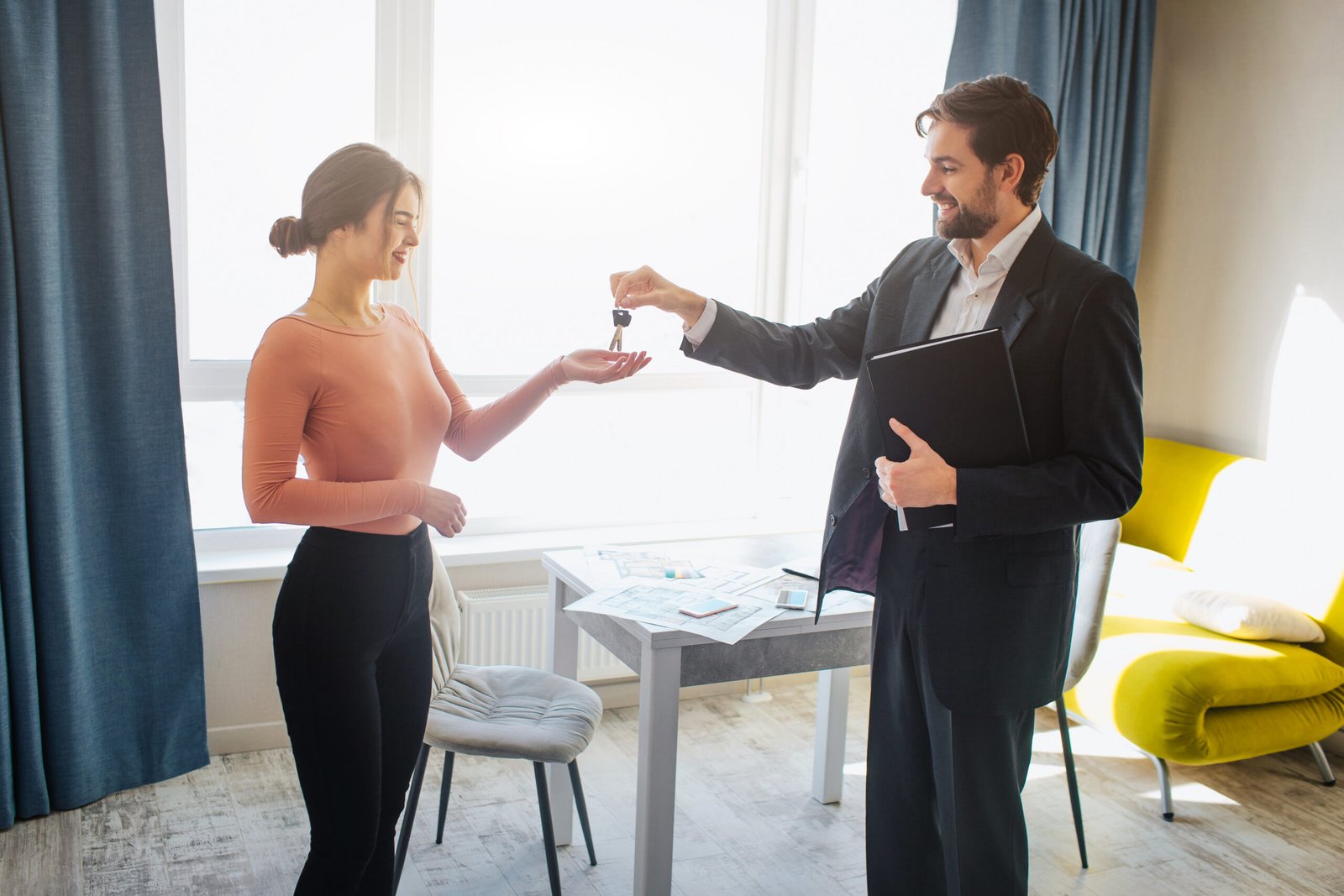 Young woman buy rent apartment. She get keys from realtor. Happy and joyful. Business deal in office room. Bright daylight